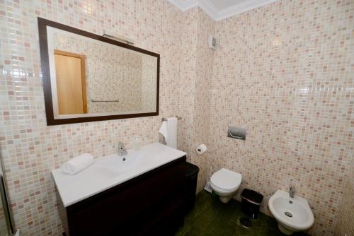 uma casa de banho com um lavatório, um WC e um espelho. em Vela - Apartment in complex near the beach em São Martinho do Porto