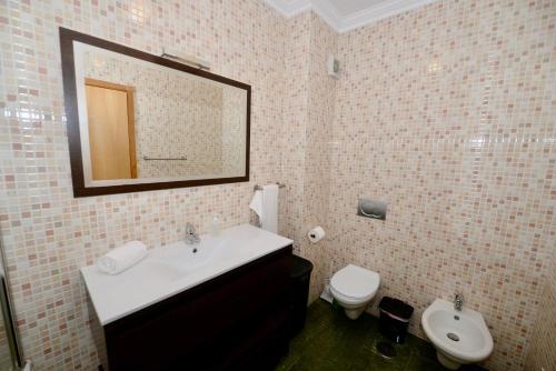 a bathroom with a sink and a toilet and a mirror at Vela - Apartment in complex near the beach in São Martinho do Porto