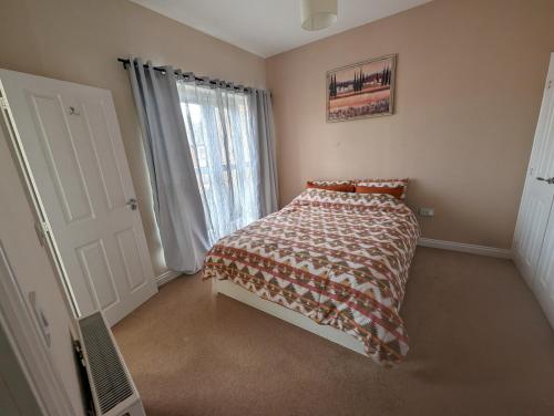 a bedroom with a bed with a comforter and a window at Dudley Rooms in Tipton