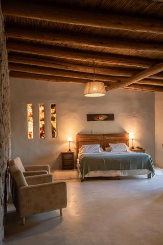 a large bedroom with a bed and a chair at Las Terrazas Hotel Boutique in Tilcara