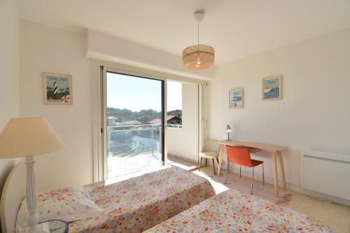 une chambre avec deux lits et un bureau et une fenêtre dans l'établissement Horizon - Hossegor appartement situé au deuxième et dernier étage d'une résidence avec ascenseur magnifique vue sur l'océan, à Soorts-Hossegor