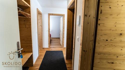 a hallway with wooden walls and a door with a rug at Haus Golmenegg, Riederalp in Riederalp