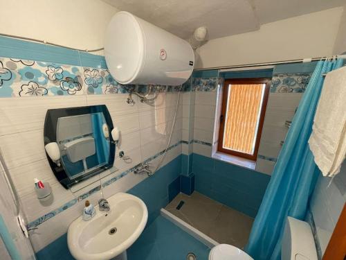 a bathroom with a sink and a toilet and a mirror at Brami Apartment in Berat