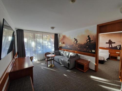 ein Hotelzimmer mit einem Sofa und einem Schlafzimmer in der Unterkunft Hotel Kompas in Kranjska Gora
