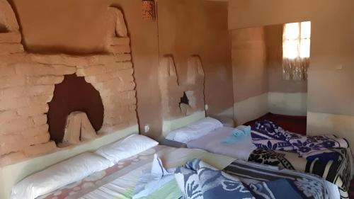 a room with two beds in front of a fireplace at Auberge Dinosaur Kem Kem in Tafraoute Sidi Ali