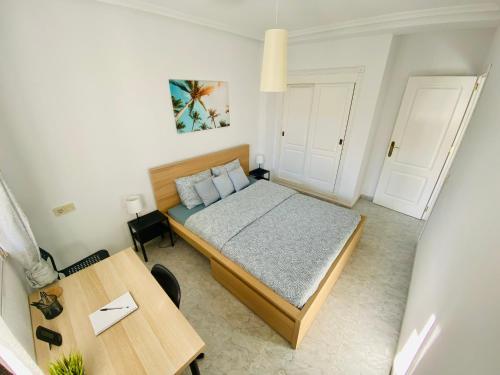 Un pequeño dormitorio con una cama y una mesa. en Sunny Penthouse close to everything, en Torrevieja