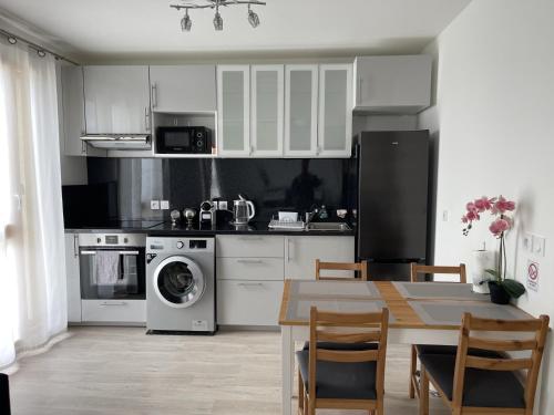 uma cozinha com armários brancos e uma mesa com cadeiras em HOUSE COSY ONE em Gonesse