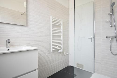 une salle de bain blanche avec un lavabo et une douche dans l'établissement Horizon - Hossegor appartement situé au deuxième et dernier étage d'une résidence avec ascenseur magnifique vue sur l'océan, à Soorts-Hossegor