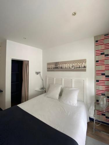 a bedroom with a white bed and a shelf with books at La Villa du Grand Large in Biscarrosse