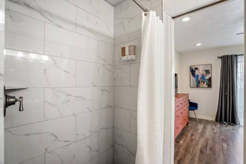 a bathroom with a shower with white marble walls at Winter Retreat 3b 3ba Huge backyard Mins from Downtown in Houston