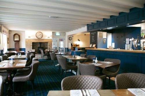 um restaurante com mesas e cadeiras de madeira e uma lareira em The Boatside Inn - Hadrian - Twin Ensuite em Hexham