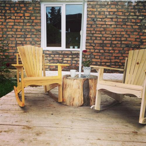 two wooden chairs sitting on a stump in front of a house at The Rolé House in Gurjaani