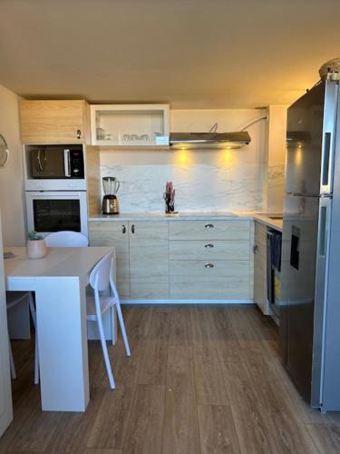 - une cuisine avec des placards blancs, une table et un réfrigérateur dans l'établissement Le petit Baigneur de la grand bleue, à Port-Leucate