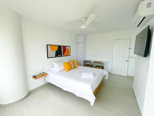 a white bedroom with a bed and a flat screen tv at Magico Apartaestudio con Piscina 1 Habitacion PR66C in Montería