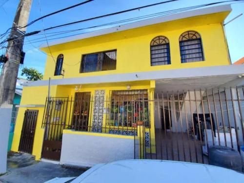 une maison jaune avec une clôture devant elle dans l'établissement Economic Studio in Santurce Area, Up to 4 guests, à San Juan