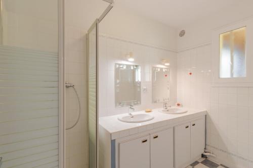 a white bathroom with two sinks and a shower at Gîte Piscine et Jacuzzi intérieurs in Cherveix-Cubas