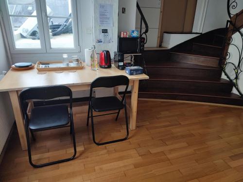 ein Schreibtisch mit zwei Stühlen in einem Raum mit Treppe in der Unterkunft Chambre double- SDB et WC Privé in Morlaix