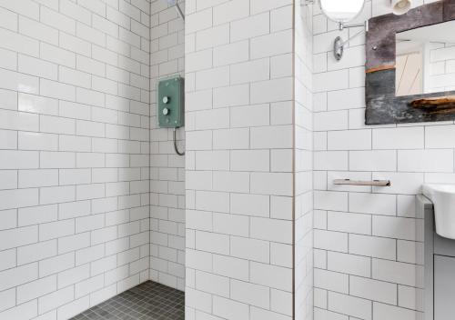 um chuveiro de azulejos brancos com um lavatório e um espelho em The Artists Studio - Syderstone em Syderstone