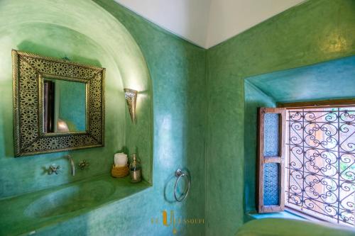 a green bathroom with a tub and a window at Riad El Youssoufi in Marrakech
