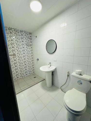 a white bathroom with a toilet and a sink at Casa Blanca Puerto Galera in Puerto Galera