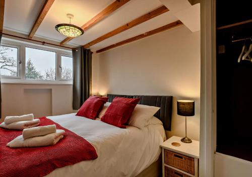 a bedroom with a large bed with red pillows at Cobbley Cottage in Little Snoring