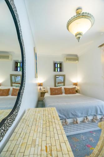 a bedroom with two beds and a large mirror at Riad El Youssoufi in Marrakech