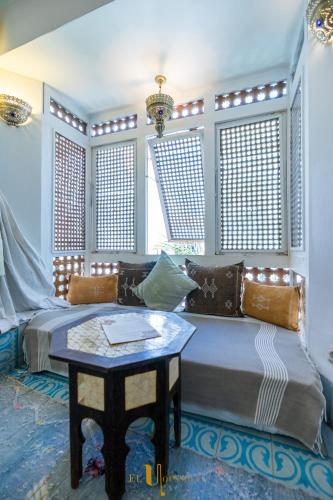 a bedroom with a bed and a table and windows at Riad El Youssoufi in Marrakech