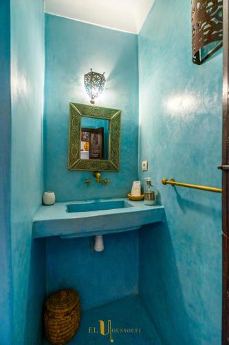 a blue bathroom with a sink and a mirror at Riad El Youssoufi in Marrakech