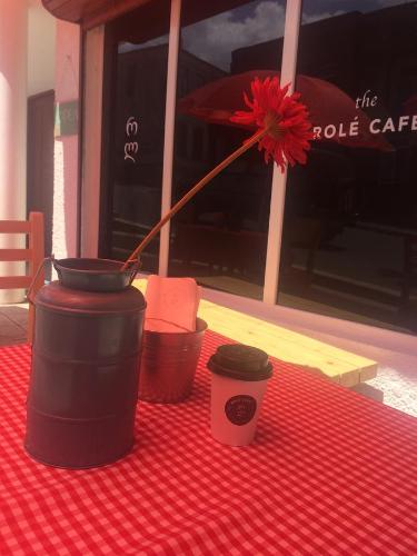 a red table cloth with two coffee cups and a red flower at The Rolé House in Gurjaani