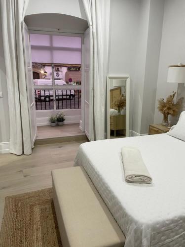 a white bedroom with a bed and a balcony at Apartamento corredera 1 in Arcos de la Frontera