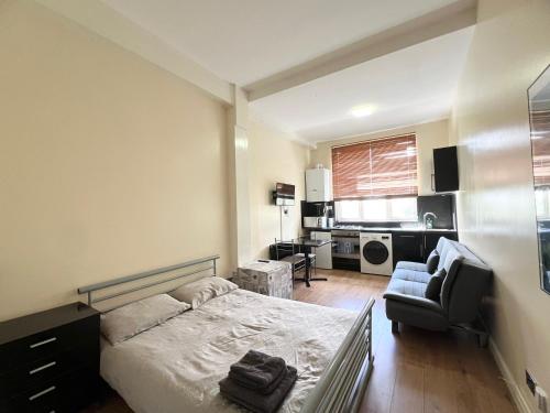 a bedroom with a bed and a chair and a kitchen at Comfy Apartments - Finchley Road in London
