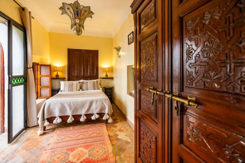a bedroom with a bed and a large wooden door at Riad El Youssoufi in Marrakech