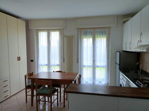 Appartamento Aeroporto e Fiera في سيرياته: مطبخ مع طاولة وكراسي خشبية وطاولة ومطبخ به