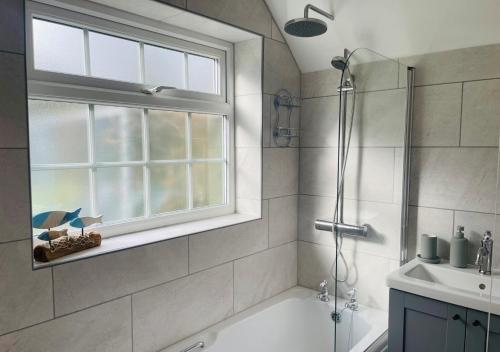 a bathroom with a shower and a tub and a sink at Badgers Hideaway in Helhoughton