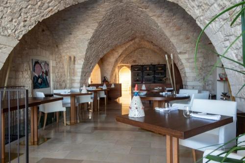 un ristorante con tavoli in legno e sedie bianche di La Sommità Relais & Chateaux a Ostuni