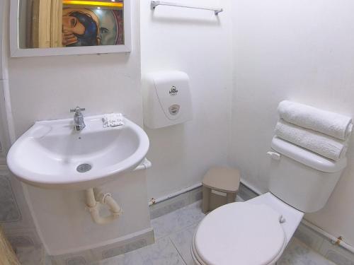Baño blanco con aseo y lavamanos en Hostal El Rey, en Baños