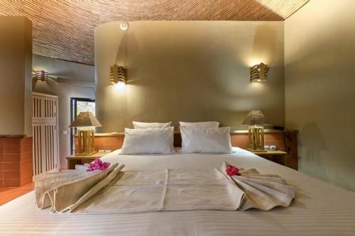 ein Schlafzimmer mit einem großen weißen Bett mit Blumen darauf in der Unterkunft Hotel Royam in Saly Portudal