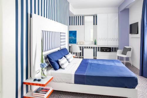 a bedroom with a blue and white bed and a kitchen at Villa Aragonese Rooms in Monte di Procida