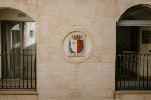 a crest on the side of a building with two windows at IBB Hotel Palazzo Bettina Malta in Birgu