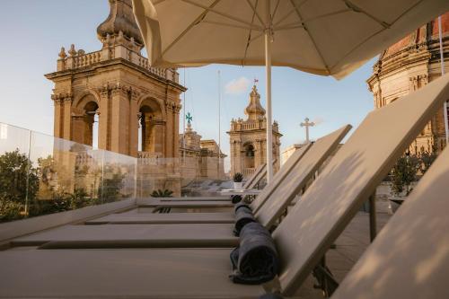 a bench with an umbrella in front of a building at IBB Hotel Palazzo Bettina Malta in Birgu