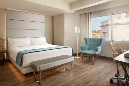 sypialnia z łóżkiem, krzesłem i biurkiem w obiekcie NH Madrid Zurbano w Madrycie