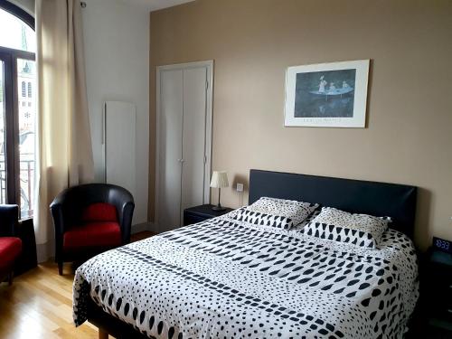 - une chambre avec un lit noir et blanc et une chaise rouge dans l'établissement T3 Astoria Grand Lac hyper centre, à Aix-les-Bains