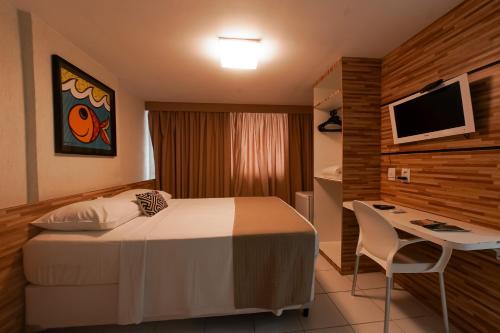 Habitación de hotel con cama, escritorio y TV. en Dublê Hotel - The Original, en Recife