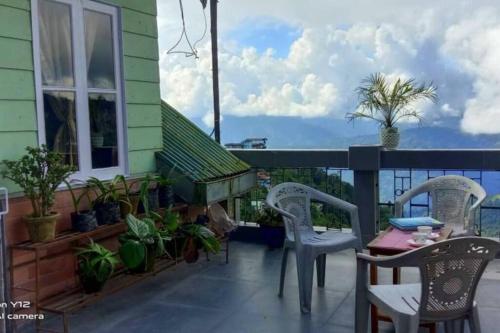 a balcony with two chairs and a table and some plants at Darjeeling CoLiving Home in Darjeeling