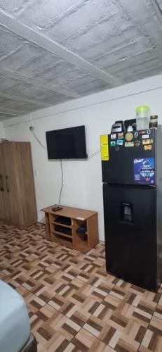 Zimmer mit einem schwarzen Kühlschrank und einem Tisch in der Unterkunft Apartatamento pequeño amueblado in San Salvador