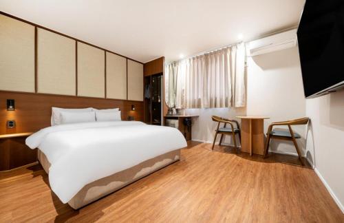 a bedroom with a large white bed and a table at H Avenue Hotel Chungjangro in Gwangju