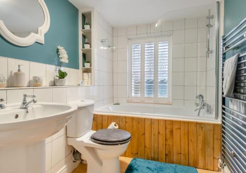 a bathroom with a toilet and a sink and a tub at The Old Mill Cottage - Norfolk in Fakenham
