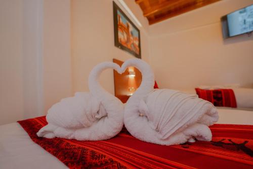 two swans shaped like a heart sitting on a bed at DANNA INN in Machu Picchu