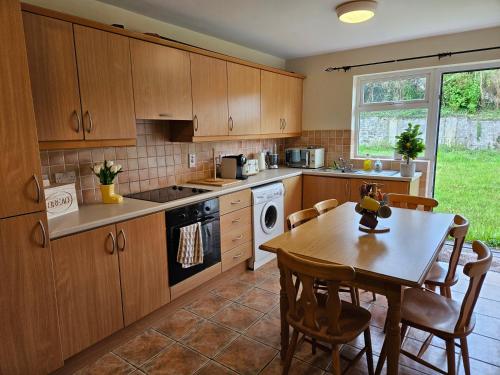 a kitchen with wooden cabinets and a table and a dining room at Phrey's Holiday Home in Kenmare