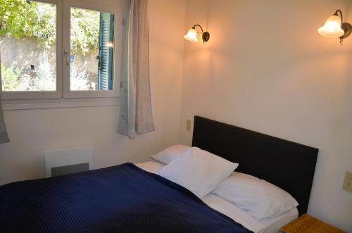 1 dormitorio con 1 cama con 2 almohadas y ventana en GRILAF - Au cœur du village typique de Grimaud appartement coquet, en Grimaud